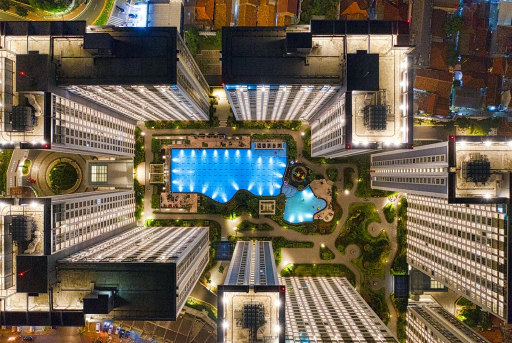 drone footage of illuminated modern urban complex with pool