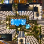 drone footage of illuminated modern urban complex with pool