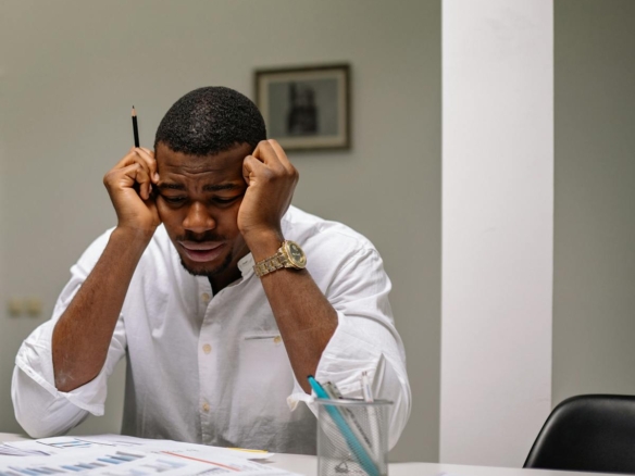 A worried businessman in corporate attire handling stress at his workspace.