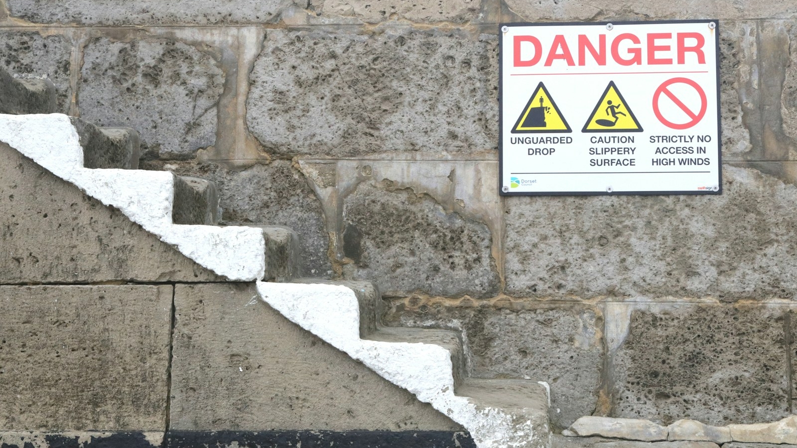 a sign on a stone wall warning of danger