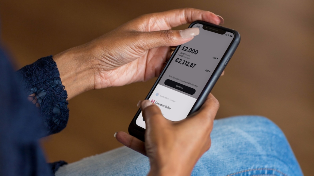 a woman holding a cell phone with finance app open in her hand